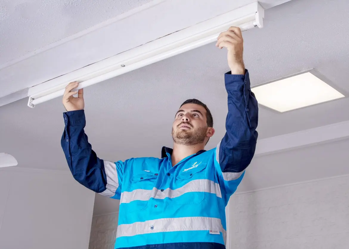 A man installing a ceiling light in a room.