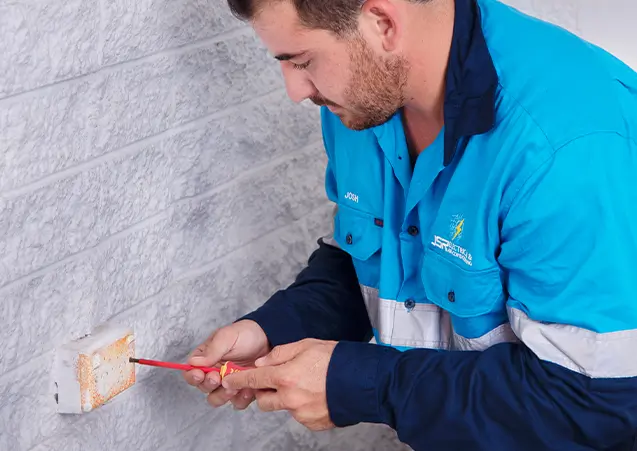 A man in a blue shirt is working on a wall.