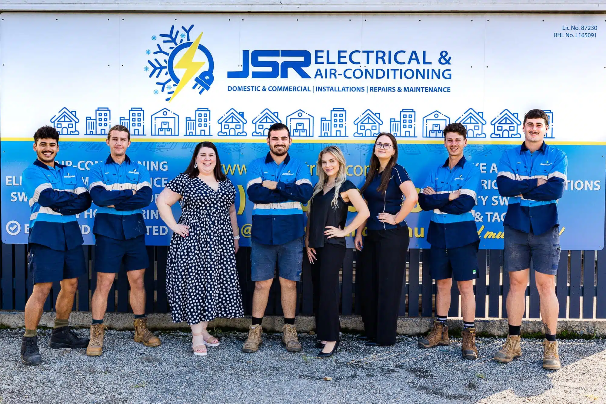 Men and women standing in front of a building sign posing.